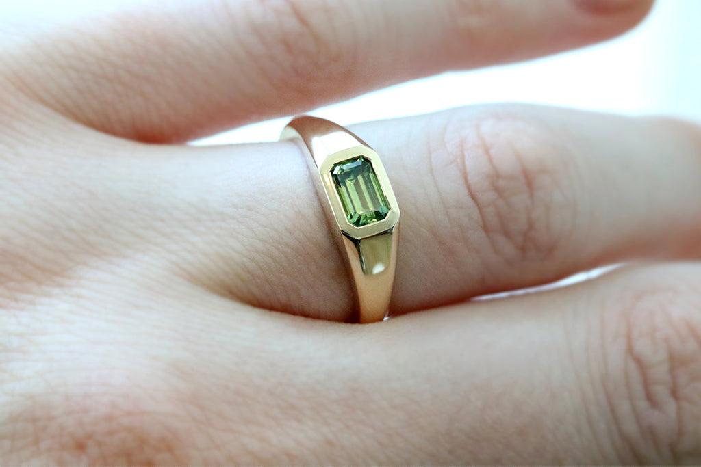 This yellow gold signet ring features a bezel set Emerald Cut Australian Sapphire, in east-west orientation. Perfectly showcasing the unique beauty of Australian sapphires, this one of a kind ring could be worn as an alternative engagement ring, or simply as a cherished everyday ring.