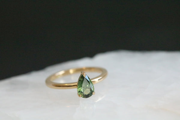 Handmade in 18ct yellow gold, this solitaire engagement ring features a Pear Cut Australian Green Sapphire, clasped in a minimalistic three prong setting.