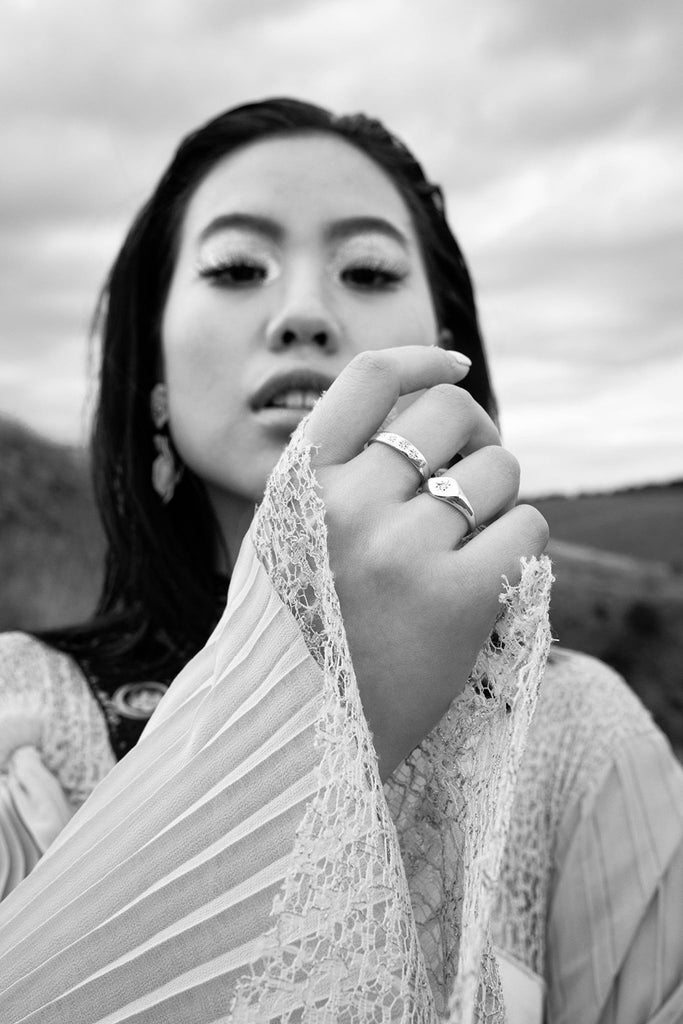 a model wearing rings holds her hand towards the centre fo the frame